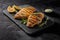 Grilled chicken fillets on slate plate. Gray concrete background