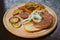 Grilled chicken meat with pickled onions and zucchini, fried potatoes, served on wooden plate