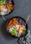 Grilled chicken, rice, spicy chickpeas, avocado, cabbage, pepper buddha bowl on dark background, top view.