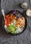 Grilled chicken, rice, spicy chickpeas, avocado mash, cabbage, pepper buddha bowl on dark background, top view.