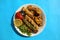 Grilled chicken shashlik, lamb, beef kofta kebab, tomato, parsley on white plate on blue background