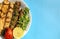 Grilled chicken shashlik, lamb, beef kofta kebab, tomato, parsley on white plate on blue background