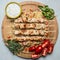 Grilled chicken on skewers with garlic sauce and bulgur dill parsley and tomatoes on a cutting board wooden background top view