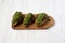 Grilled chimichurri chicken breast on a rustic wooden board on a white wooden surface, low angle view