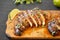 Grilled chipotle chicken breast on a rustic wooden board on a black surface, side view. Close-up