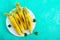 Grilled corn with herbs and sea salt on a white plate on a bright background.