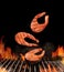 Grilled delicious salmon steaks are falling down on black background. Barbecue bbq grill, flaming fire, ember charcoal