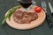 Grilled, delicious steak of veal, beef or pork, tomato, rosemary and soy sauce for meat on round wooden board, knife and fork,