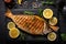 A grilled fish beautifully presented on a slate plate, accompanied by slices of fresh lemon. AI generated