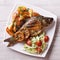 Grilled fish with fried potatoes and salad top view, closeup