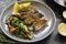 Grilled fish with lemon, herbs and rosemary. Fried fish fillets in a grey plate. Beautiful presentation of food. Rucolla