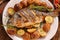 Grilled fish with roasted potatoes and vegetables on the plate