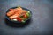 Grilled fish salmon steak with vegetables salad on ceramic plate on rustic stone background angle view, balanced diet