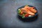 Grilled fish salmon steak with vegetables salad on ceramic plate on rustic stone background angle view, balanced diet