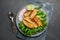 Grilled fish sea bass fillet with green lettuce in a plate on a black stone background