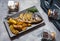 Grilled fish on stone plate with lemon on concrete background