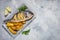 Grilled fish on stone plate with lemon on concrete background, top view