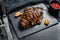 Grilled Flat Iron steak on a stone Board, marbled beef. Black background. Top view