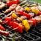 Grilled food, skewers and sausages with herbs and vegetables on a cast iron grate