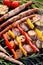 Grilled food, skewers and sausages with herbs and vegetables on a cast iron grate