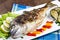 Grilled gilt head sea bream on plate with lemon ,salad and grill