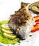 Grilled gilt head sea bream on plate with lemon ,salad and grill