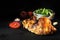 Grilled half chicken on a dark slate plate with salad and tomato