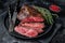 Grilled hanger or Onglet beef meat steak on a plate with thyme. Black background. Top View