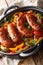 Grilled Italian sausages with bell pepper close-up in a pan. vertical