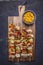 Grilled kebabs with peppers, pork and pineapple on a cutting board with sauce on wooden rustic background top view close up