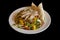 Grilled lean meat. The side dish is grilled vegetables with pita bread. Food on a white plate isolated on a black background