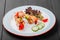 Grilled meat kebabs on skewers with vegetables, cherry tomato, pepper, zucchini in plate on dark wooden background.