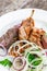 Grilled meat on plate, chicken legs, beef steak and onion on wooden background close up