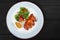 Grilled meat steak and salad with grilled vegetables, arugula and spinach in plate on dark wooden background.