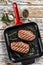 Grilled meat Top Blade steaks in a frying pan. Gray background. Top view