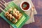 Grilled meatballs skewer and sweet chili dipping sauce on wooden background - Thai appetizer called Look Chin Ping