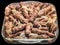 Grilled Minced Meat Loafs Cevapcici With Chopped Onion In Glass Baking Dish Isolated On Black Background