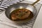 Grilled peppered pork chop in a brass pan with thyme