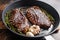 Grilled picanha organic  beef steaks on pan with herbs and garlic. Over old dark metall background, side view wide angle