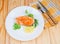 Grilled piece of arctic char with vegetables, fork and knife