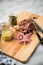 Grilled pork knuckle meat on wooden cutting board with pickled gherkins, sweet and medium hot mustard on marble background