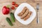 Grilled pork sausages in plate, sweet pepper, cucumbers, tomato