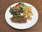 Grilled Pork Steak with black pepper sauce served with vegetables salad and frenchfries.