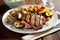 Grilled pork steak with bone in tamarind sauce, with lemon and tomatoes close-up on a plate on the table