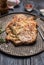 Grilled pork steak on an iron baking tray with a fork and pepper on wooden background, close up