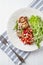 Grilled Pork Tenderloin with Tomato Salsa and Arugula. White wooden background.