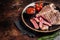 Grilled porterhouse beef meat Steak, cooked t bone in a plate with tomato. Dark background. Top view. Copy space