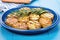 grilled potato dish, rosemary garnish on blue ceramic platter