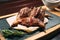 Grilled quails on the wooden plate on the table