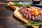 Grilled ramp cap steak on a cutting board. Dark wooden background. Top view. Copy space